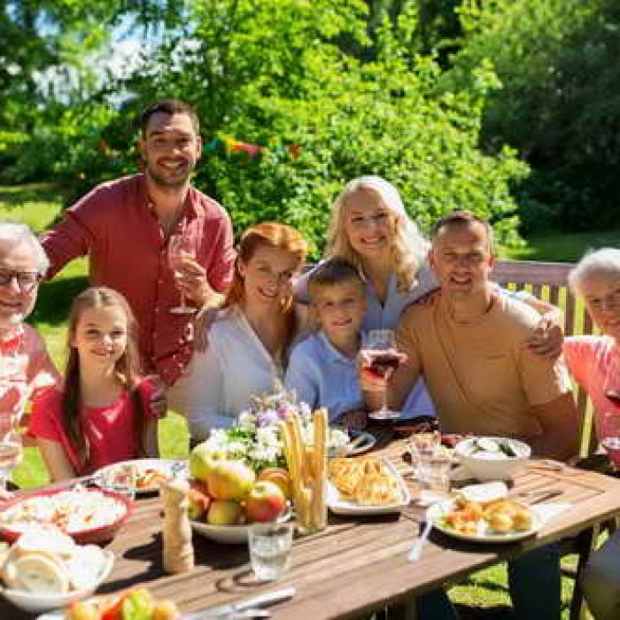 leisure, holidays and people concept - happy family having festive dinner or summer garden party and celebrating